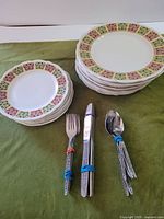 Stacked dinner and side plates with tied flatware on green cloth