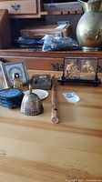 Overview of the lot showing the brass bell, cork art, wooden flute, coasters, and figurines on a wooden table.