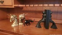 Overview of all items together showing the unicorn bookends and rhino figurine arranged on a wooden shelf.