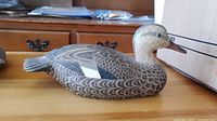 Side view showing the full profile of the carved and painted duck decoy with detailed wing feather patterns and white accent