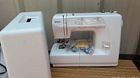 Kenmore sewing machine with detachable extension table, accessories in plastic bag, and manual included.