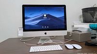 iMac with display on desk, showing keyboard and two mice