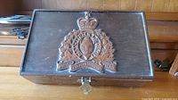 Full view of cigar box lid showing carved RCMP emblem and brass latch