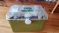 Green plastic sewing box with clear lid and top crack visible