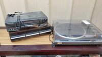Photo of the Electrohome VCR and Technics SL-Q200 turntable with cords visible, placed on a wooden surface against a beige background.