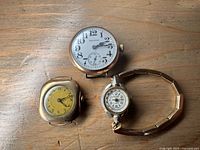 Three watches arranged on wooden surface