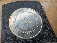 Close up of the Canadian Silver Centennial Confederation Medal showing the text Confederation 1867-1967 and a stylised maple leaf design.