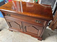 Angled front view showing full-width drawer, panel doors and scalloped base