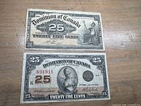 Two Dominion of Canada shinplaster currency bills placed on wooden surface. Top bill dated 1900 signed Boville, bottom bill dated 1923 signed Campbell-Clark.