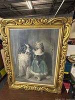 Frontal view of the framed engraving showing the girl and dog image with hand tinting and ornate gold frame.