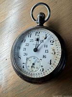 Front view of Elgin railroad pocketwatch showing cracked and discolored porcelain dial with black and red numerals, beveled crystal and metal case with patina.