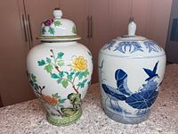 Photo showing both ginger jars side by side on a granite surface to display size and design differences.