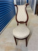 Front view of Victorian harp-backed chair showing the shaped wood backrest, upholstery, and front legs.