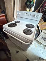 Front angle view of white Kenmore electric stove with coil burners and control panel.
