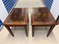 Photo showing pair of rectangular wooden lamp tables with leather tops and gold trim, positioned side by side