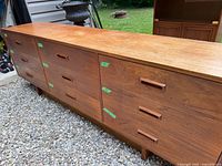 Front angle view of the full nine drawer dresser showing wood texture and finish, with green tape markings on multiple drawer fronts.
