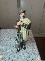 Full front view of the ceramic figurine The Laird by Royal Doulton, showing detailed face, attire, and walking stick.