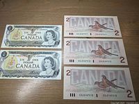 Front view of two uncirculated sequential Canadian $1 banknotes and three sequential $2 banknotes showing front designs with Queen Elizabeth II portraits and serial numbers.