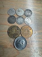 Top-down view of nine Canadian coins arranged on a wooden surface. Varied silver and brass coins including two large brass coins with beaver design dated 1942, several silver coins with wreath design, and one large silver-tone coin featuring a rabbit and dated 1967.