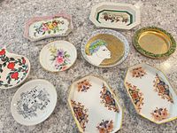 Collection of various small decorative plates and dishes shown from a top angle on a countertop surface