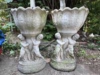 Front view of both planters showing scalloped bowls and cherub bases