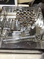 Top-down photo showing a variety of Craftsman sockets and a ratchet inside a metal tin, highlighting the range of socket sizes and types.