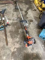 Full view of Echo gas powered weed trimmer lying on floor showing overall condition and plastic damage on the shroud.