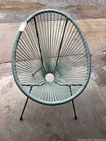 Photo of egg-shaped chair made with woven strings and metal frame, showing front view and design details.