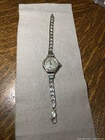 Full view of the vintage watch with gold-filled case and heavy sterling silver chain bracelet on a fabric surface.