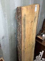 Full view of solid pine live edge slab showing natural bark on long edge and smooth finished face