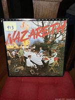 Front cover of the Nazareth album 'Malice in Wonderland' showing picnic scene with band name in red letters.