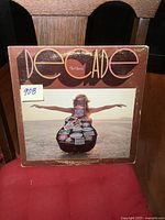 Front cover of Neil Young's 'Decade' triple LP album showing a person on the beach holding a sticker-covered guitar.