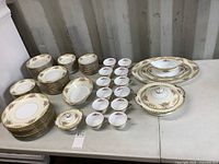 Full set of Noritake china laid out on table showing plates, bowls, cups, saucers, covered vegetable dish, platters, gravy boat, and sugar dish.