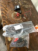 12V automatic float charger with attached alligator clips, wires and power adapter, on a wooden surface