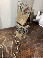 Side view of the vintage brass stained glass light showing floral embossing on the brass panel and colored stained glass insert panels in blue, green and red.