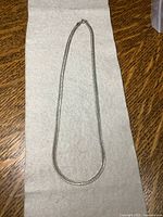 Full view of the entire 16 inch sterling silver herringbone chain necklace laid flat on a towel.