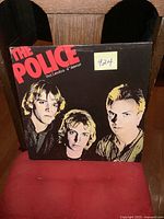 Front cover of the vinyl album showing the band members and title in red text.