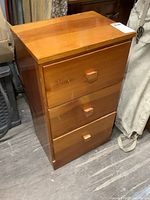Front view of vintage wooden nightstand showing three drawers with square knobs