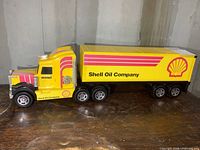 Side view of the large yellow and red Buddy L Shell Oil Company transport truck on wooden surface