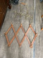 Wooden folding wall rack and metal magazine rack on wood floor, showing aged condition and details