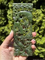 Front view of jade plaque held in hand, showing one side dragon carving