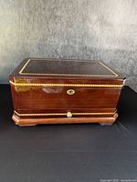 Closed view of high quality polished solid wood jewelry chest with decorative gold inlay and brass lock.