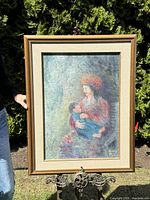 Frontal view of framed oil painting of mother and child, detailed view of figure and spirit faces in background