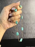 Hand holding antique 9ct rose gold chain necklace with natural turquoise boulder stones, showing length and stone detail.