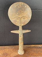 Full front view showing the large circular face and crossbar arms of the wooden Ashanti fertility doll.
