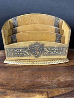 Front view of the tan leather letter holder showing embossed lion crest on front and floral scroll designs