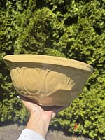 Side view of the large beige ceramic mixing bowl showing embossed floral patterns and textured rim.
