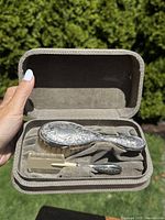 Top view of the open box showing the sterling silver child's brush and comb inside, resting on a soft fabric lining.