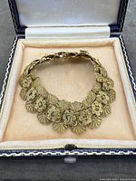 Front view of the antique gold-tone filigree bracelet displayed inside its presentation box showing detailed design and box interior.