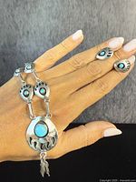 Necklace and earrings displayed together on hand against gray background